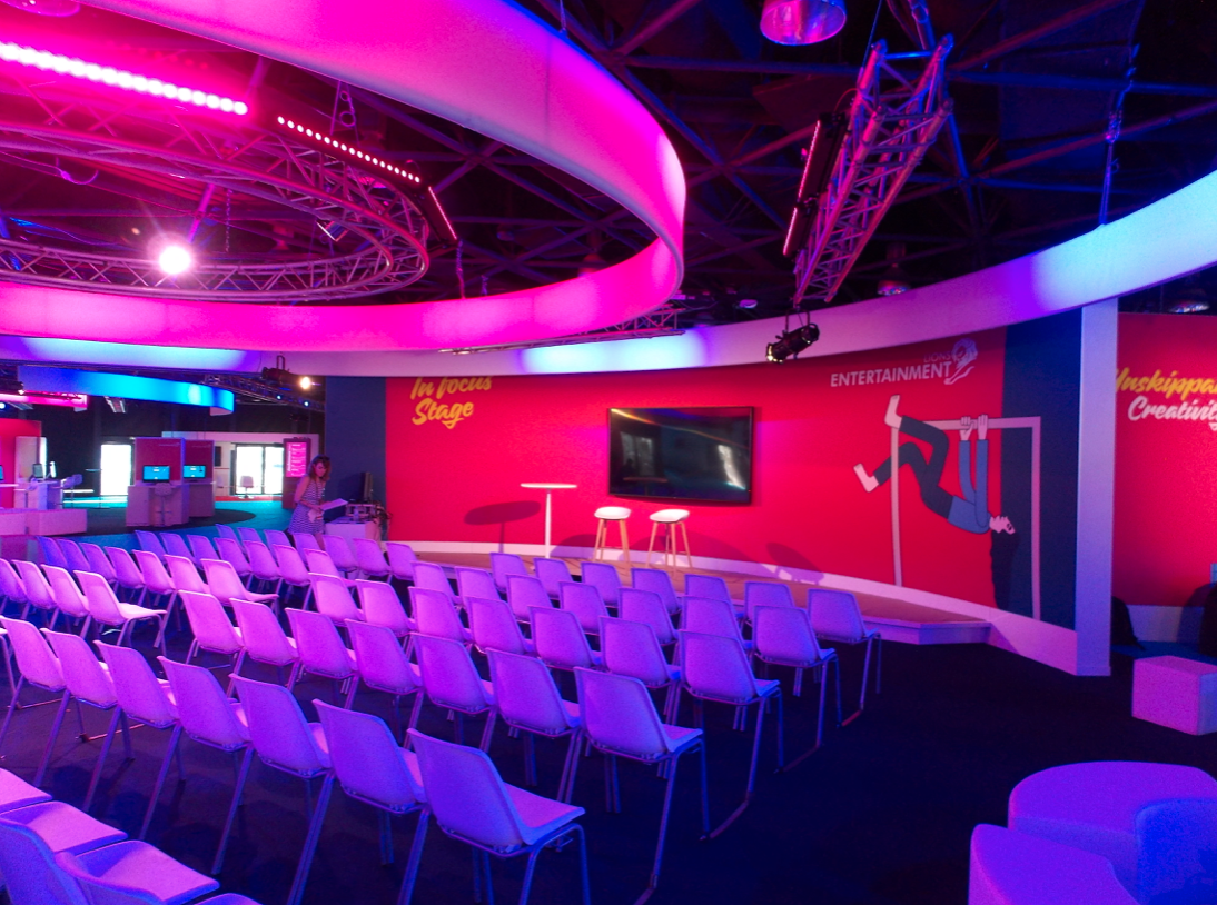 Rows of chairs are lined up in a room with purple lights