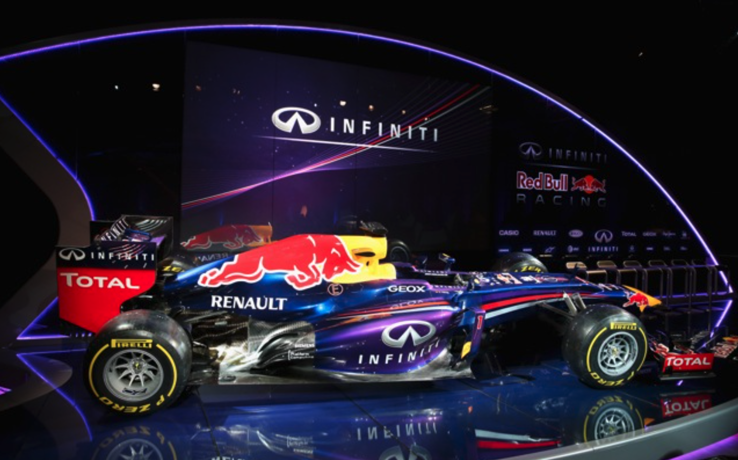 A red bull racing car is on display on a stage.