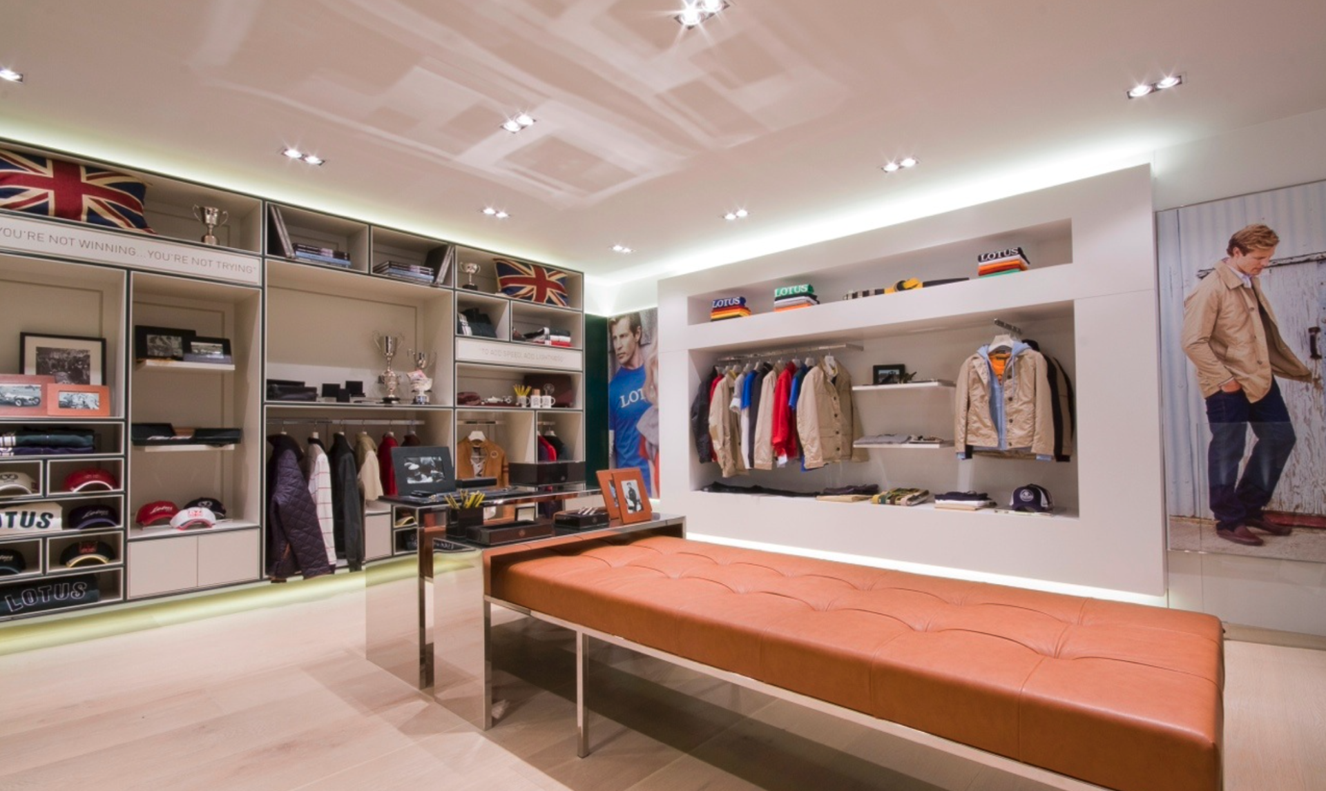 There is a bench in the middle of the room in a clothing store.