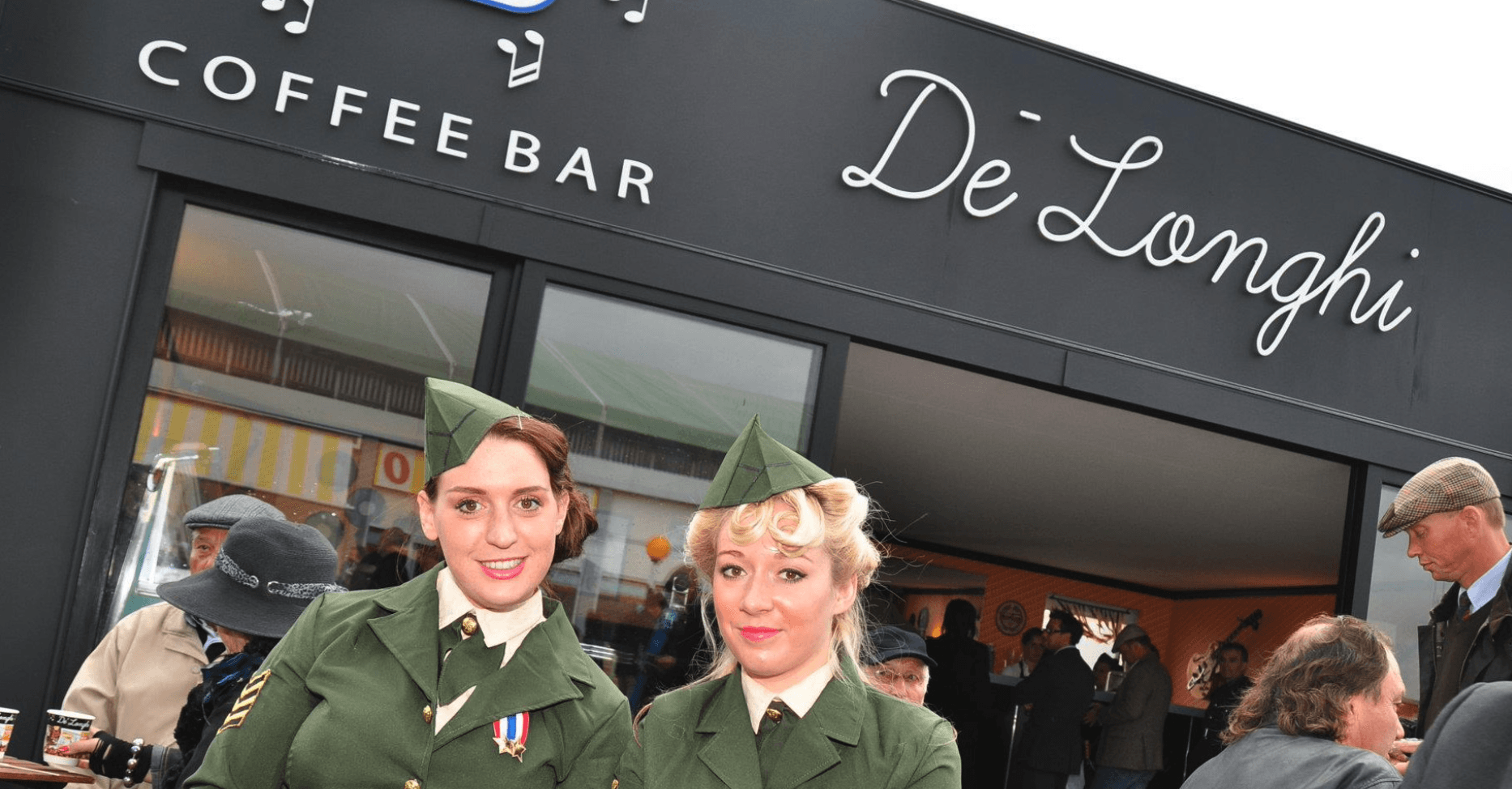 Two women in military uniforms are standing in front of a coffee bar.