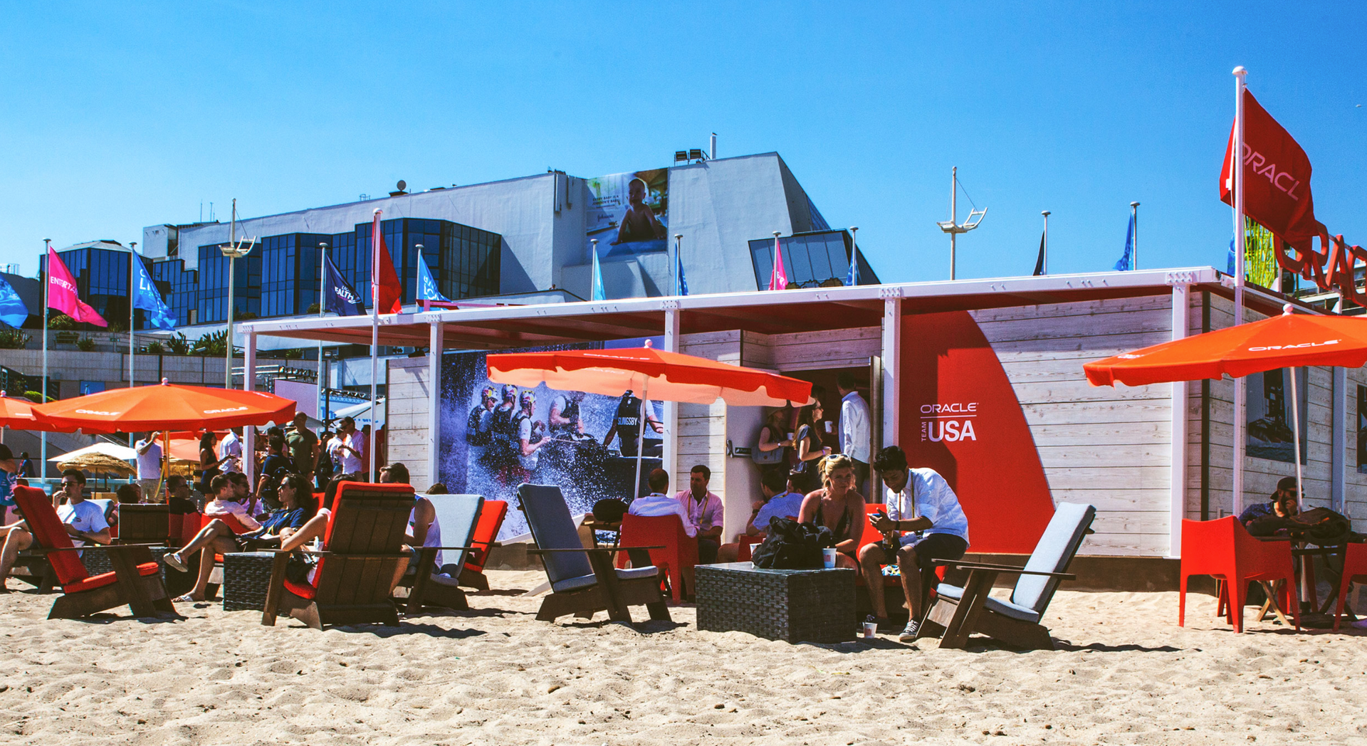 A group of people are sitting under umbrellas on a beach.
