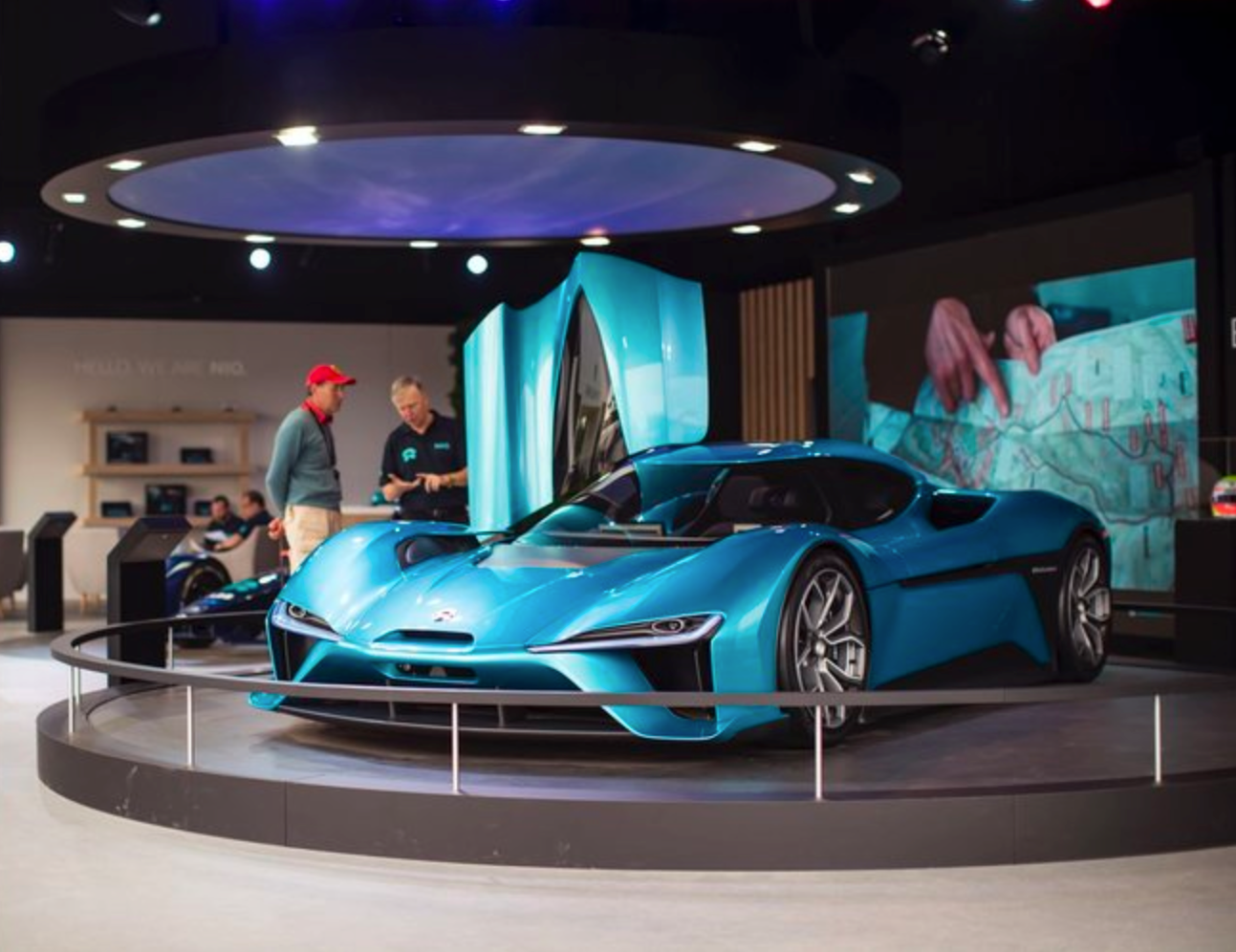 A blue sports car is on display at a car show
