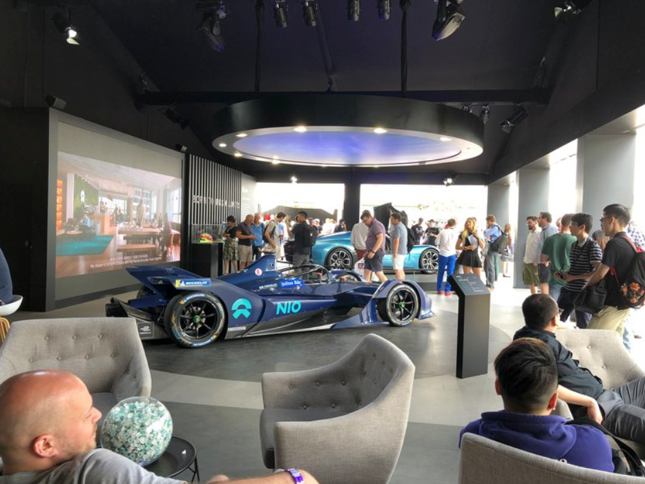 A group of people are sitting in chairs in front of a race car.