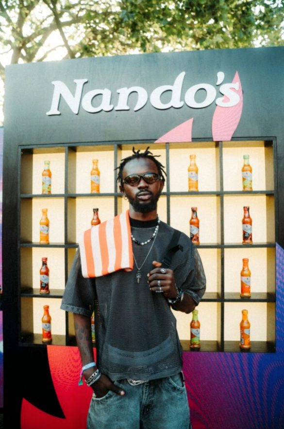 A man standing in front of a nando 's sign