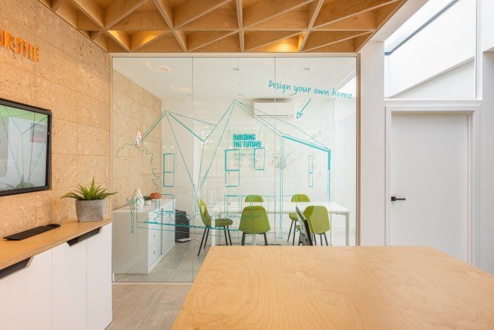 A conference room with a glass wall and a wooden table and chairs.