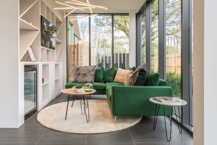 A living room with a green couch and a lot of windows.