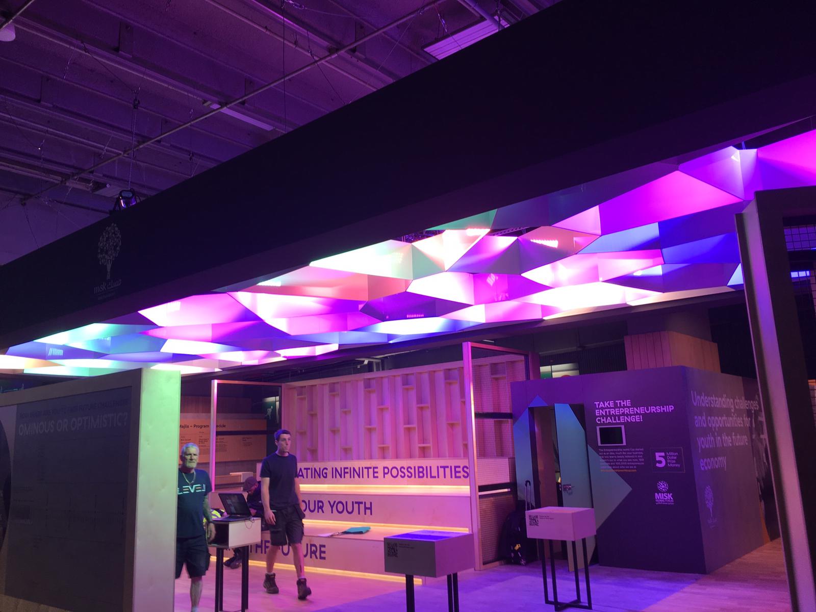 A man is standing in a room with a lot of lights on the ceiling.