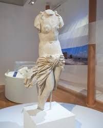 A statue of a woman without a head is on display in a museum.