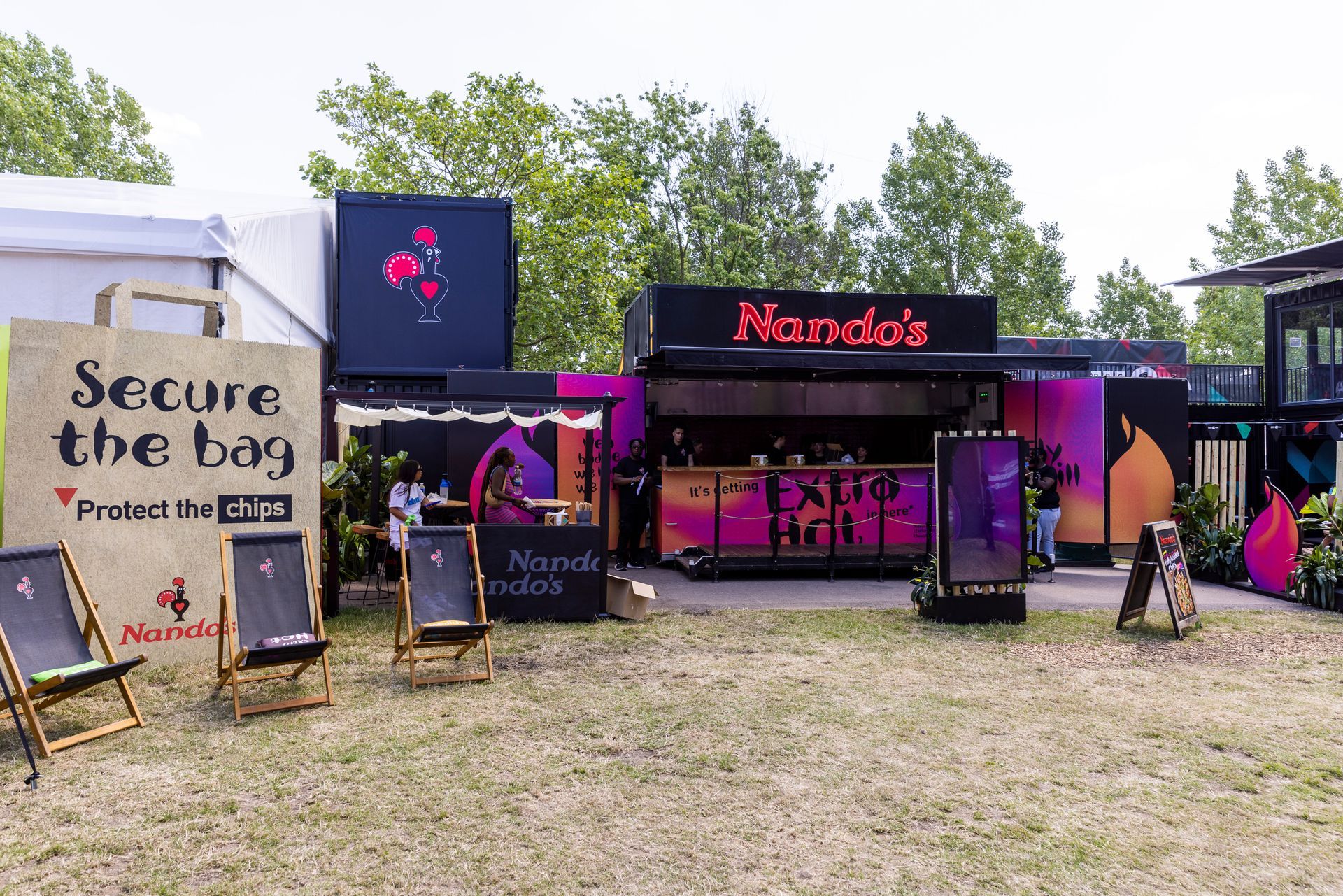 A restaurant called nandos is sitting in the middle of a field.