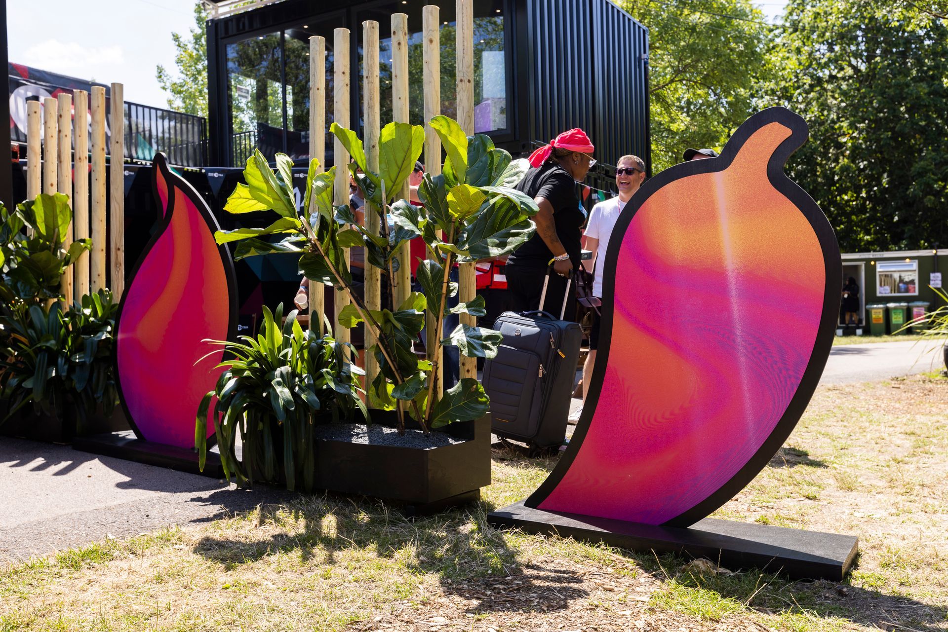 A group of people are standing in front of a sculpture of a chili pepper.