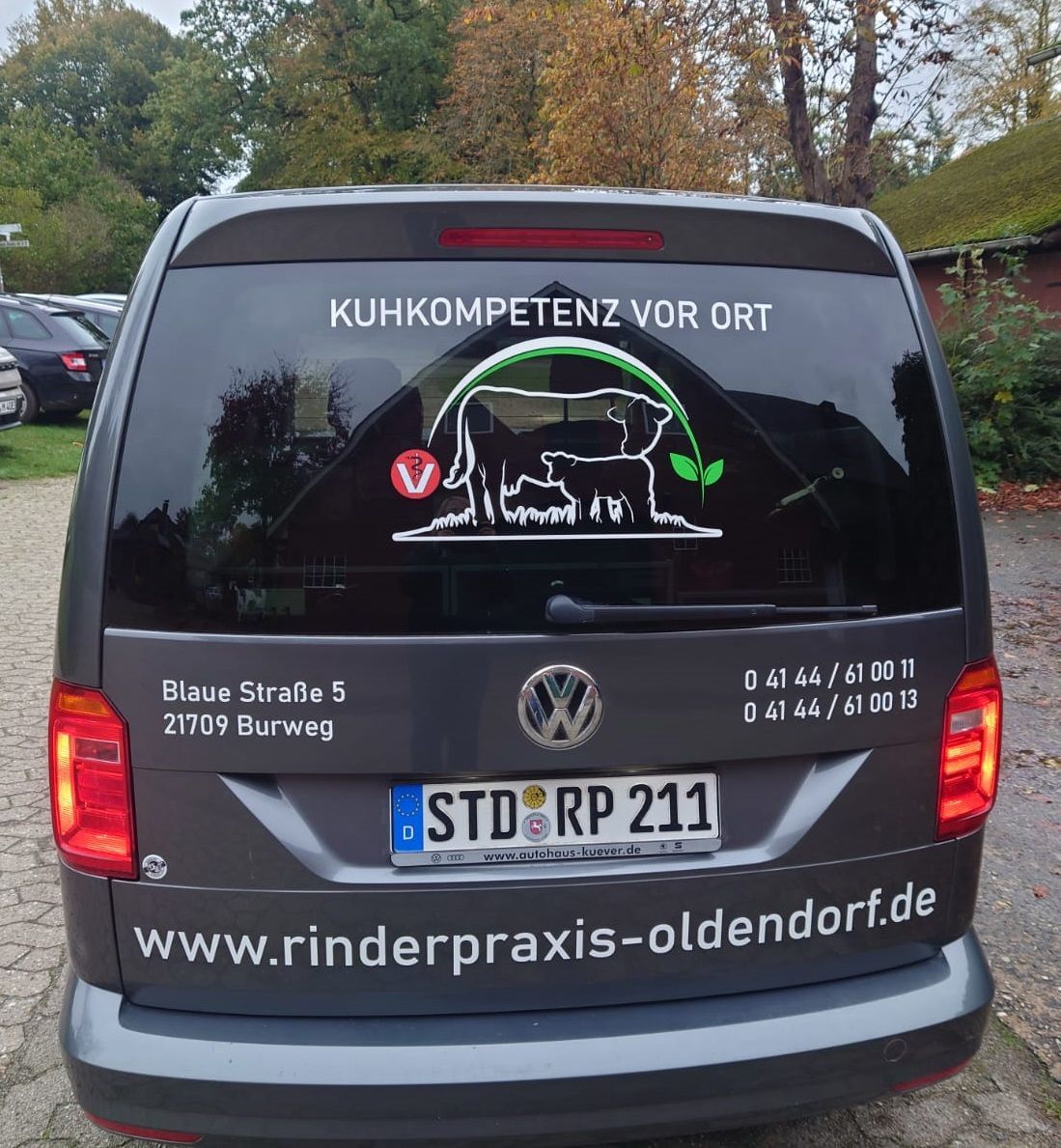 Grauer Lieferwagen mit dem Schriftzug „KUHKOMPETENZ VOR ORT“ und Kuhlogo. Kennzeichen: STD RP 211. Webseite: rinderpraxis-oldendorf.de.