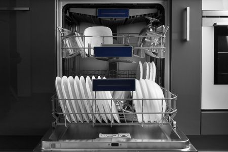 A black and white photo of a dishwasher filled with plates and glasses.