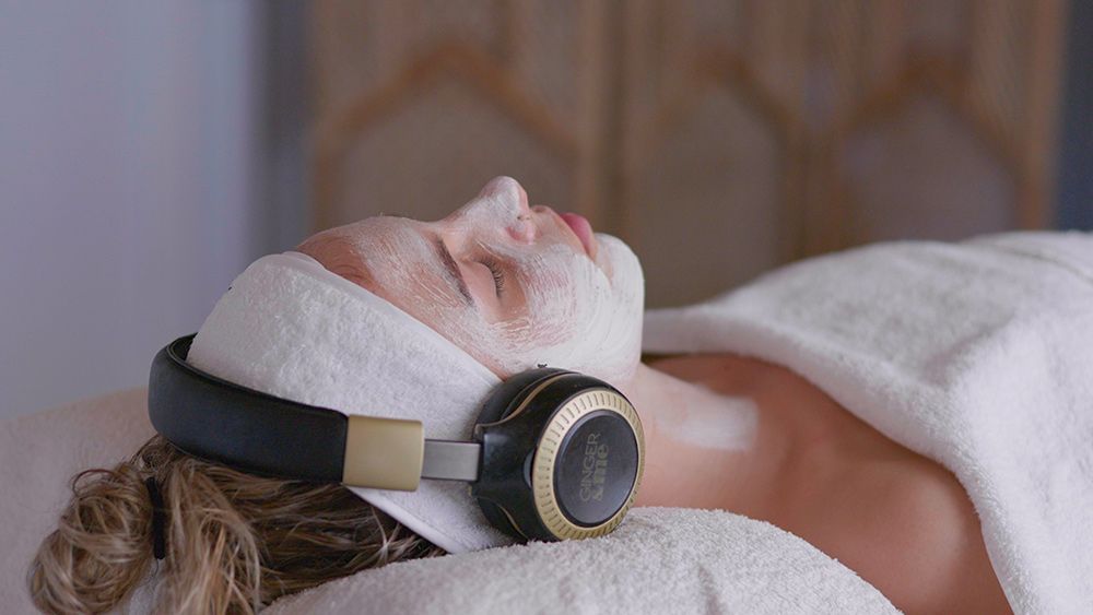 A Woman Is Laying on A Massage Table with Headphones on Her Head — Figtree Day Spa in Sawtell, NSW