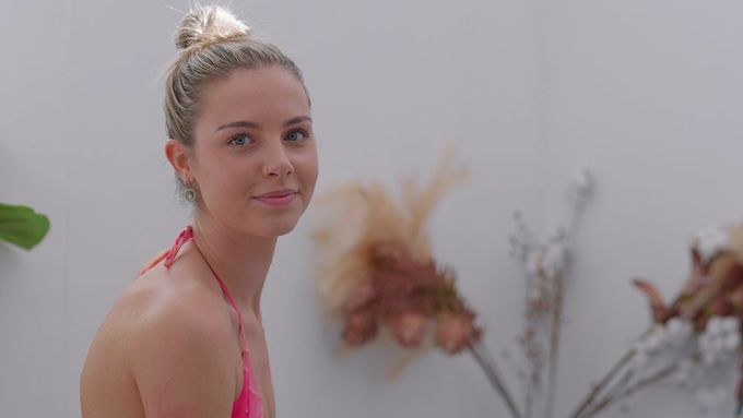 A woman in a pink bikini is standing next to a vase of flowers — Figtree Day Spa in Sawtell, NSW