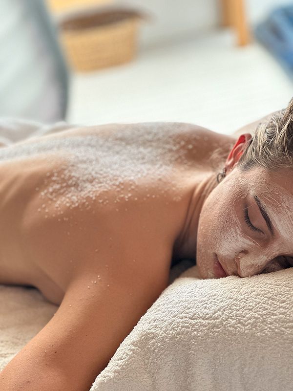 A Woman Is Laying on A Massage Bed with Powder on Her Back — Figtree Day Spa in Sawtell, NSW