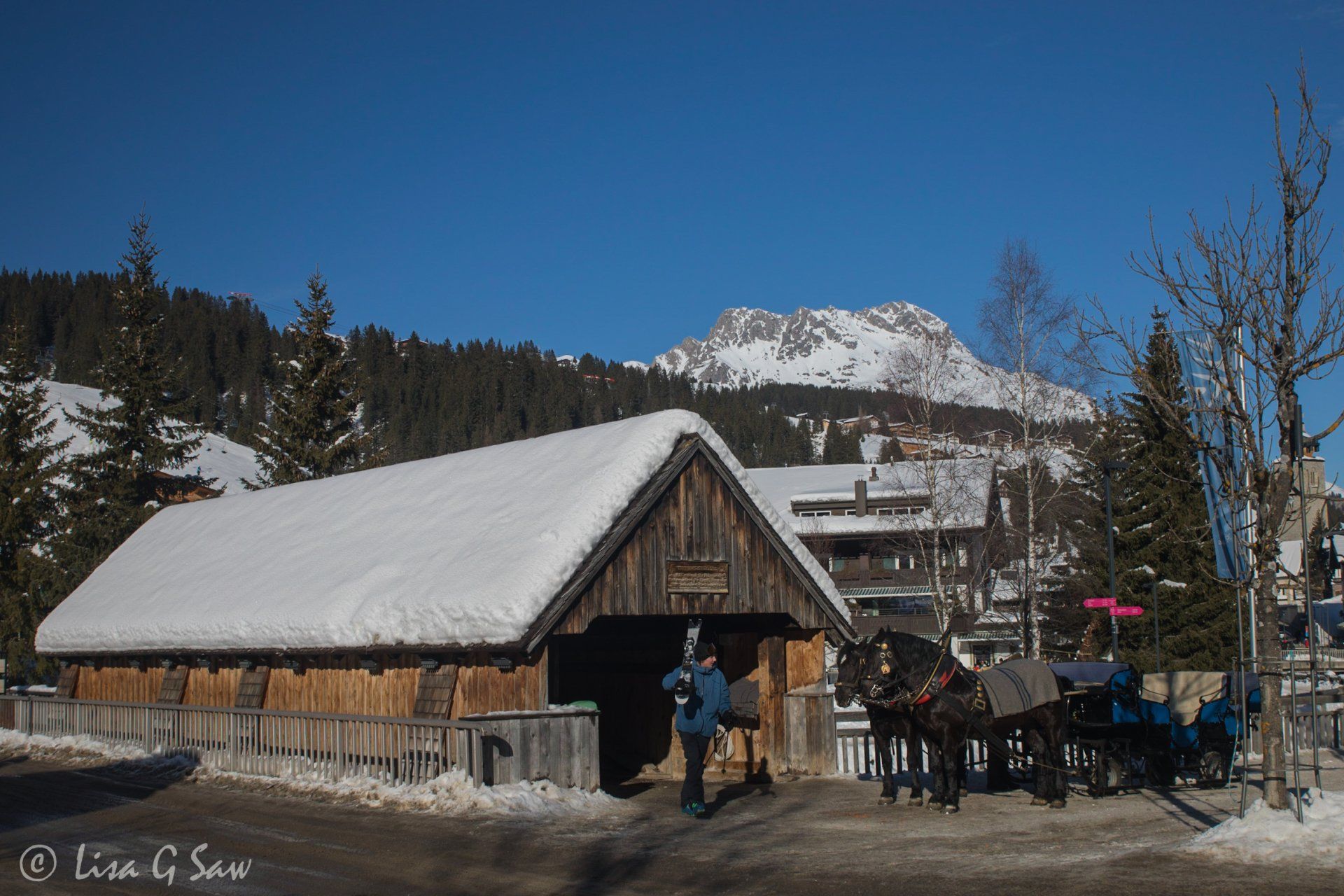 Covered bridge with skier walking and horse drawn carriage in Lech