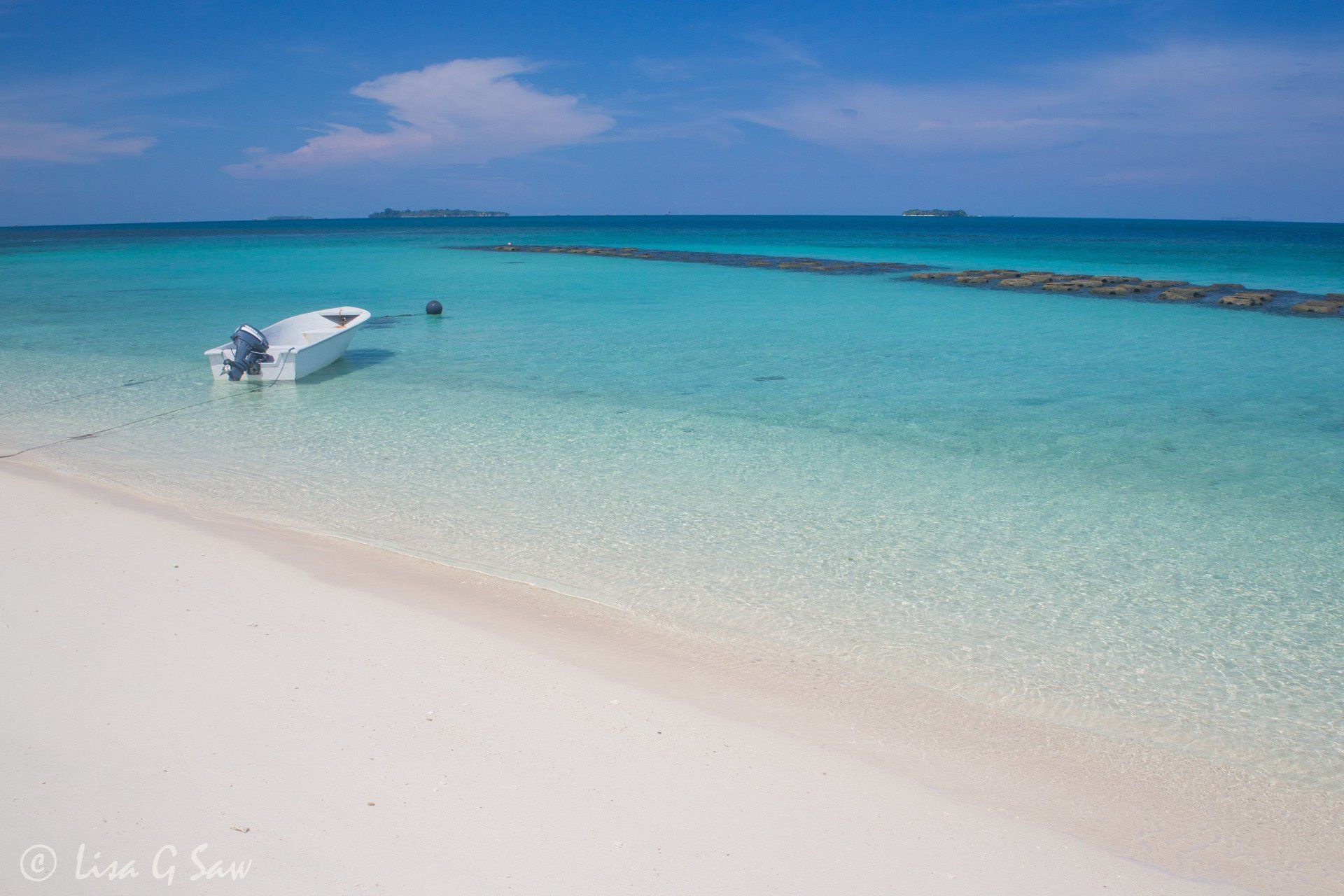 White boat moored on sandy beach in turqouise waters on Turtle Island