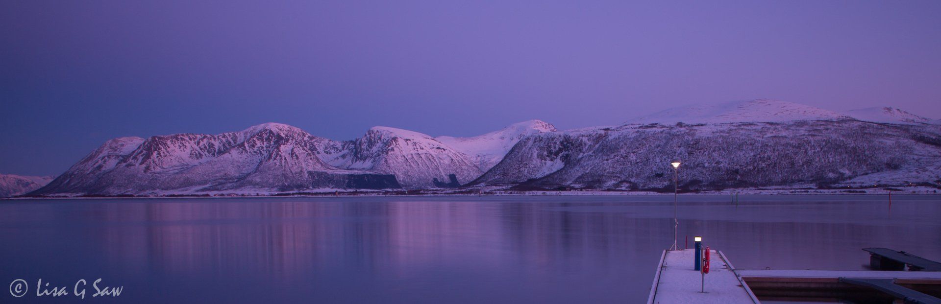 Snow covered mountains and jetty at twilight