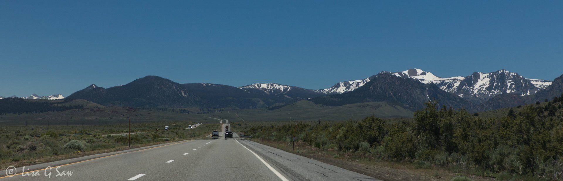 Long straight road towards snow capped mountains