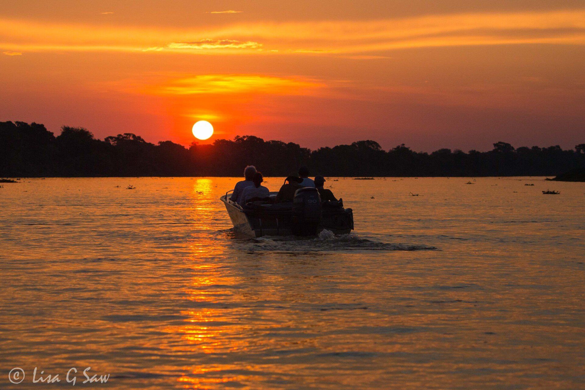Speed boat travelling on river towards sunset