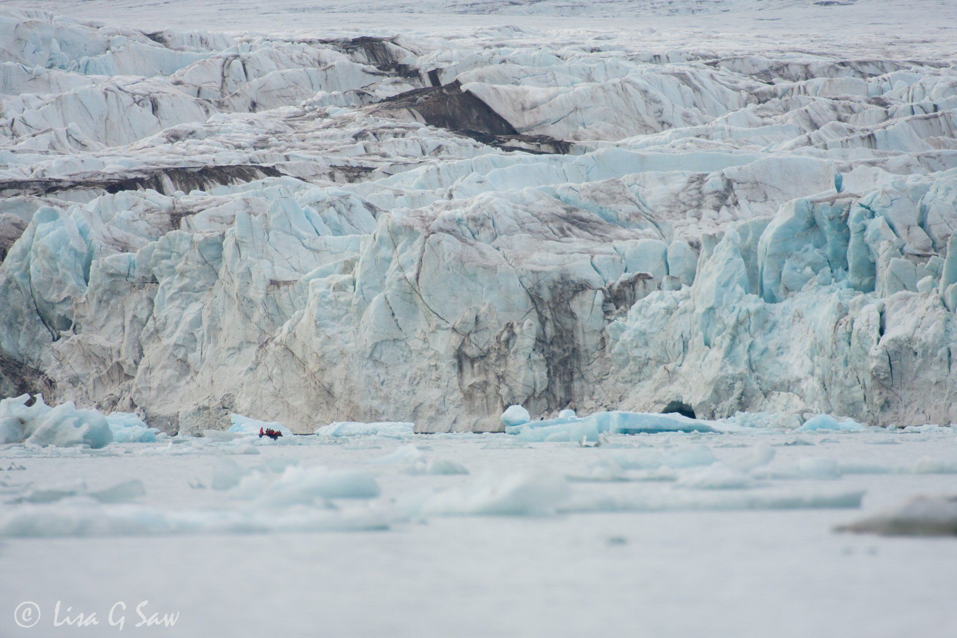 People in zodiac boat dwarfed by Monaco Glacier, Svalbard