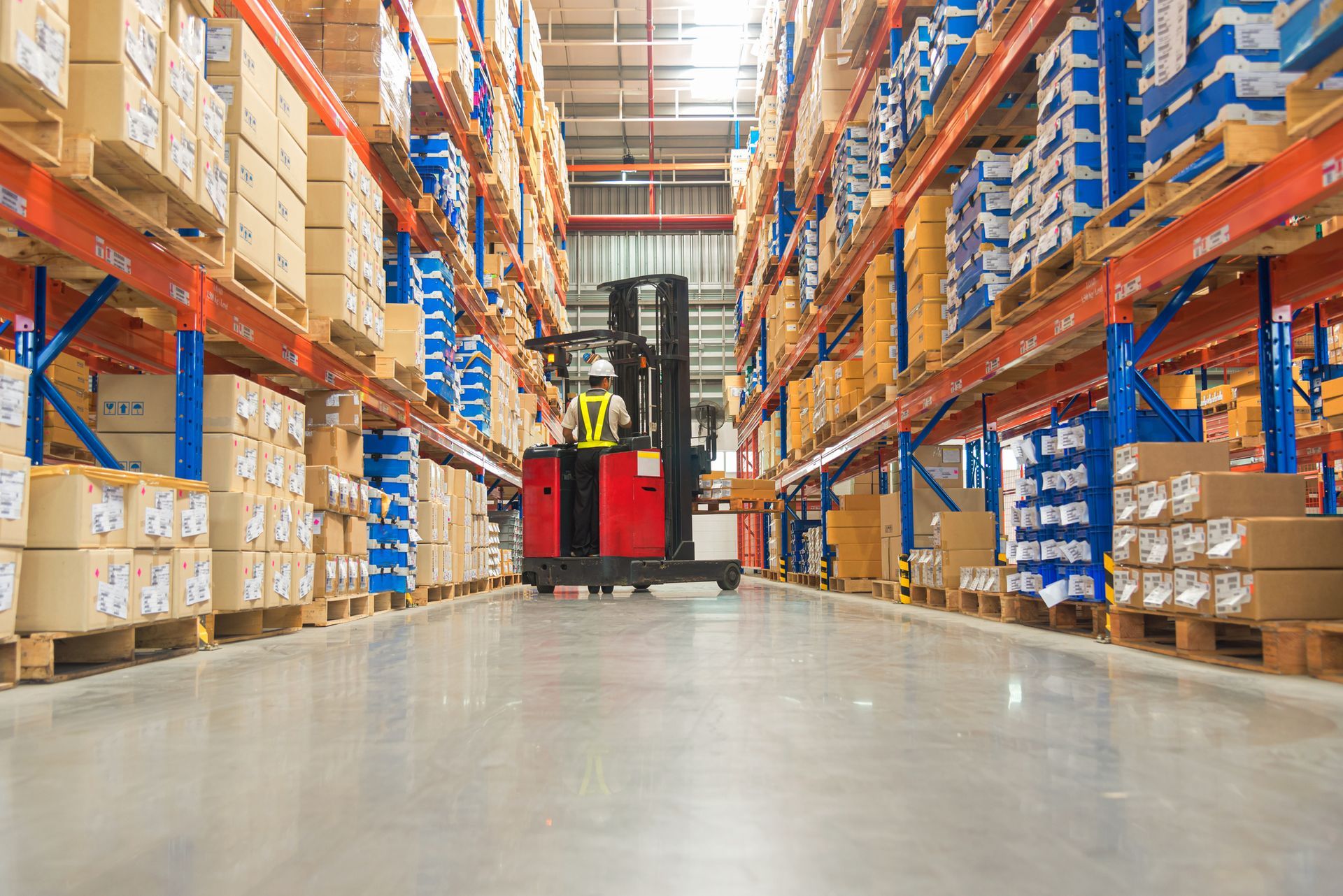 A man is driving a forklift in a large warehouse.