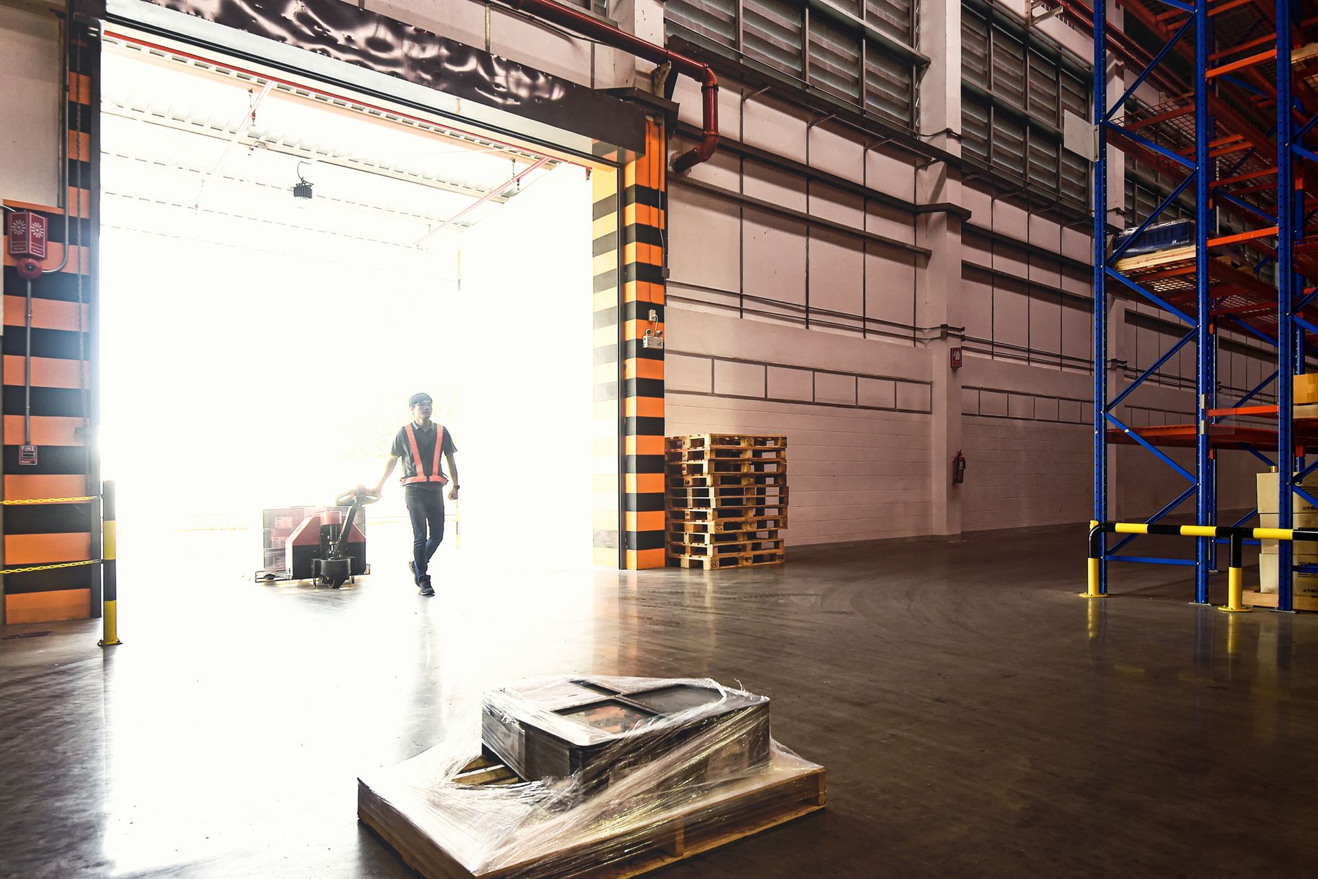 A man is pushing a cart in a warehouse.