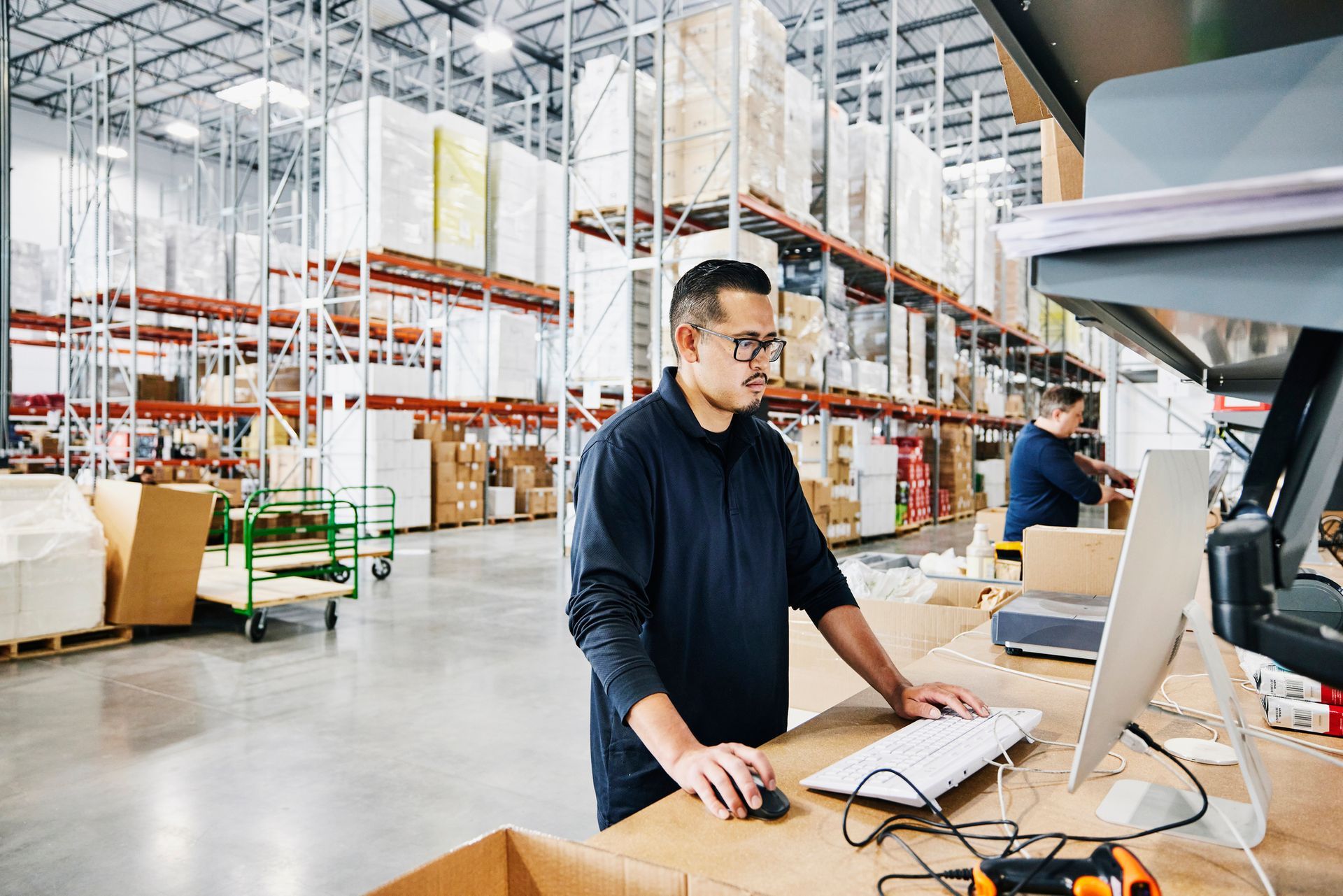 A man is working on a computer in a warehouse.