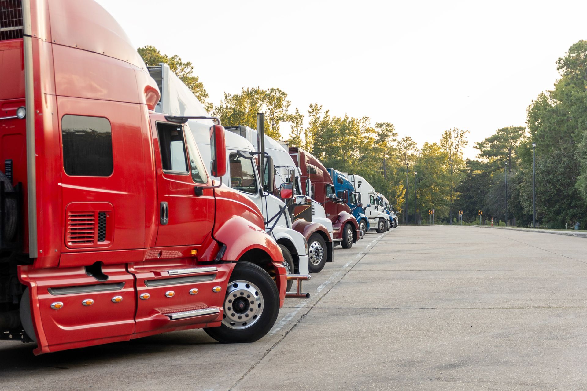 A row of semi trucks are parked in a parking lot.