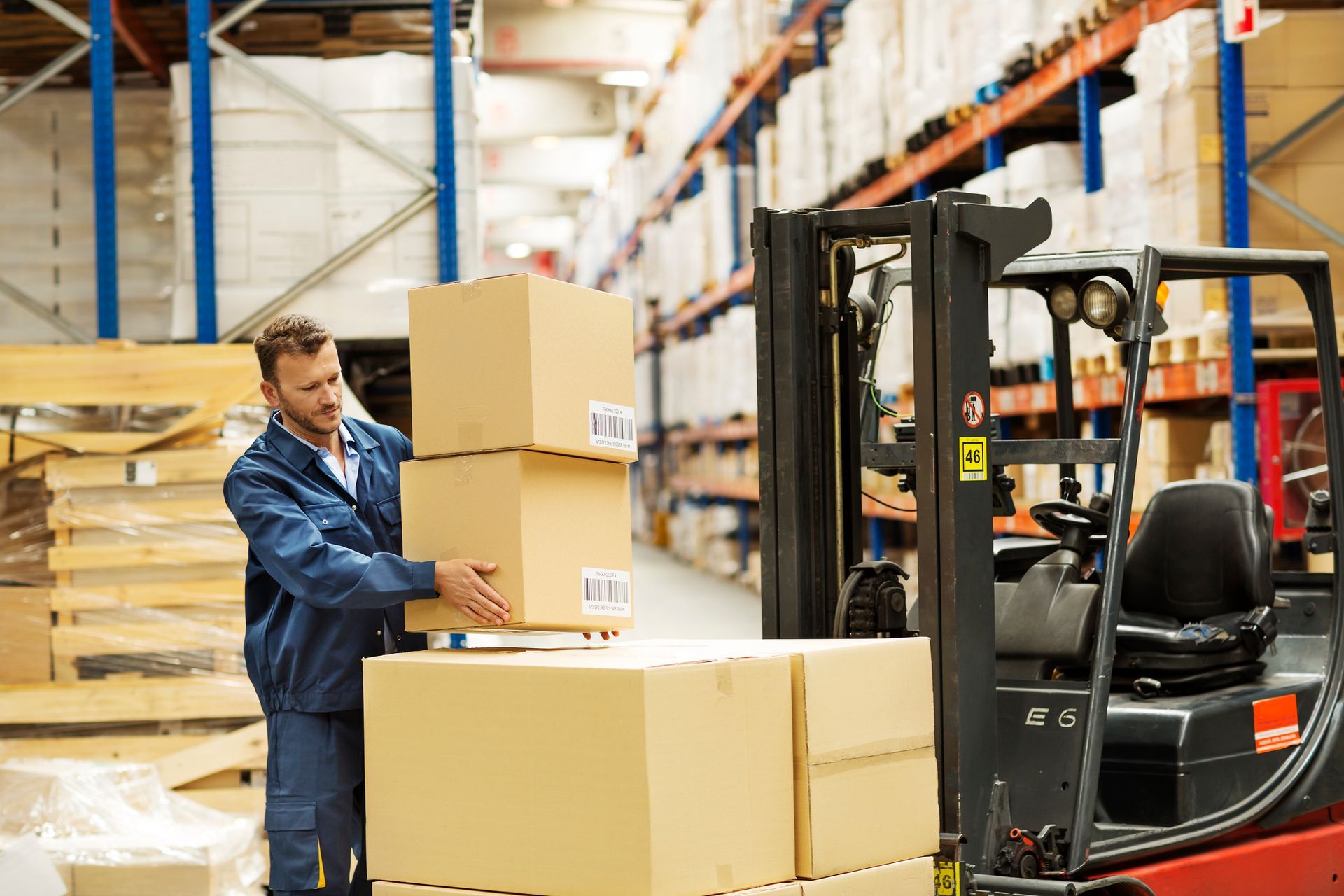 A man is loading boxes on a forklift in a warehouse.
