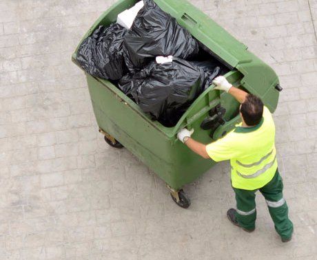 Man from city service pulling garbage bin