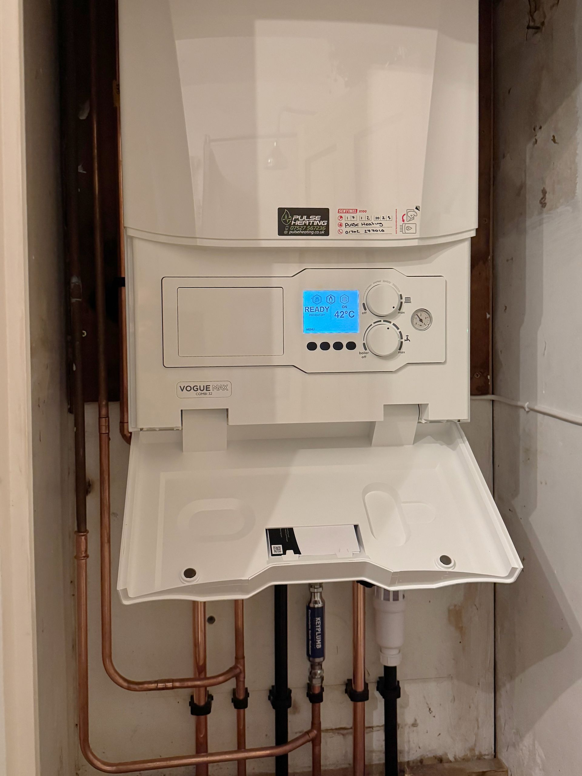 White gas boiler with a digital display and copper pipes.