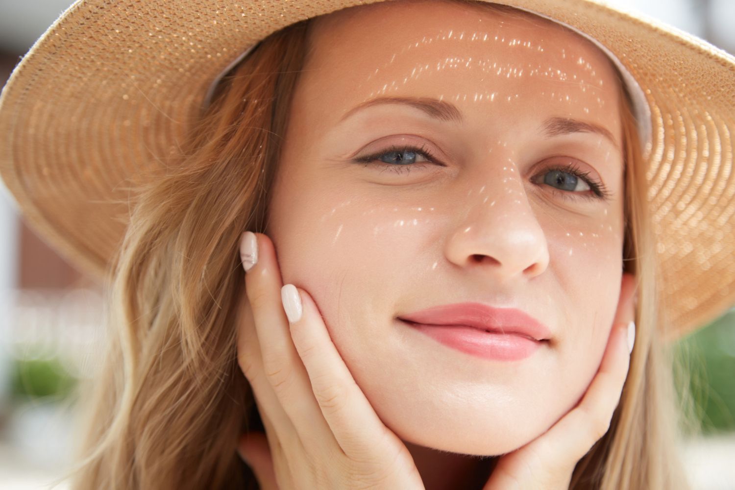 A close up of a woman wearing a hat and touching her face.