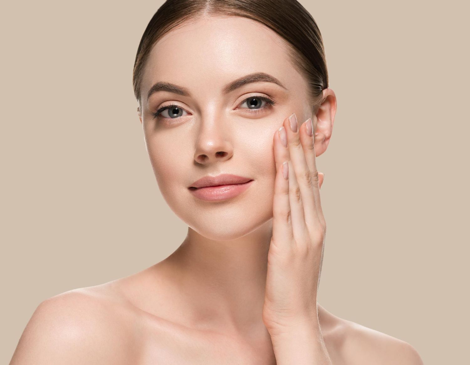 A woman is touching her face with her hand and smiling.