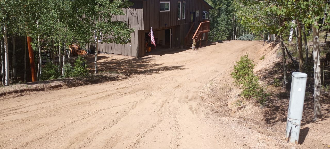 A dirt road leading to a house in the woods