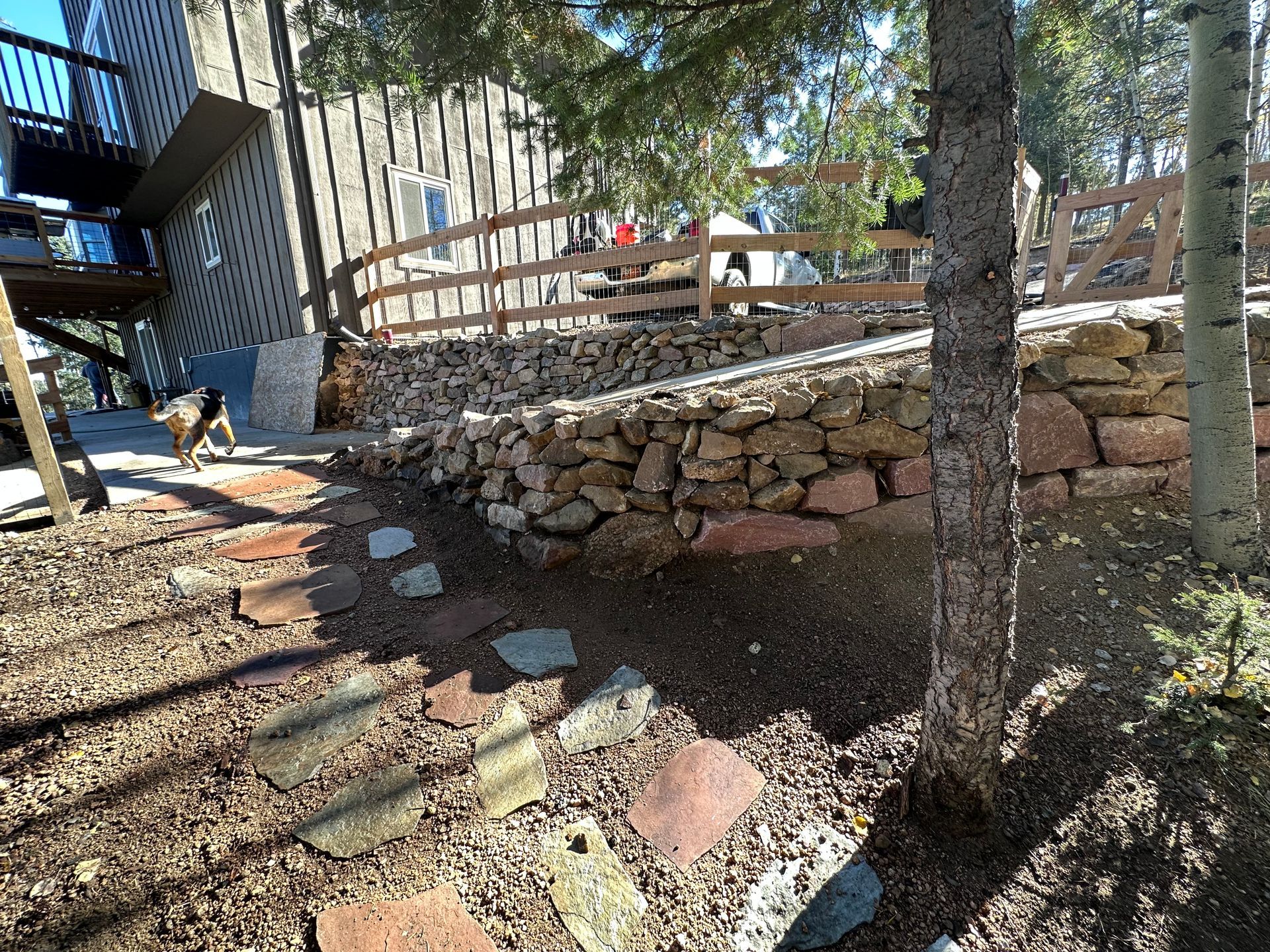 A stone wall with a wooden fence in the background