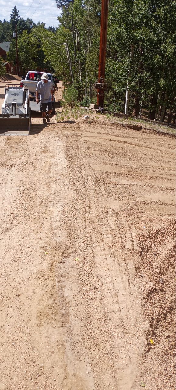 A man is driving a bulldozer down a dirt road.