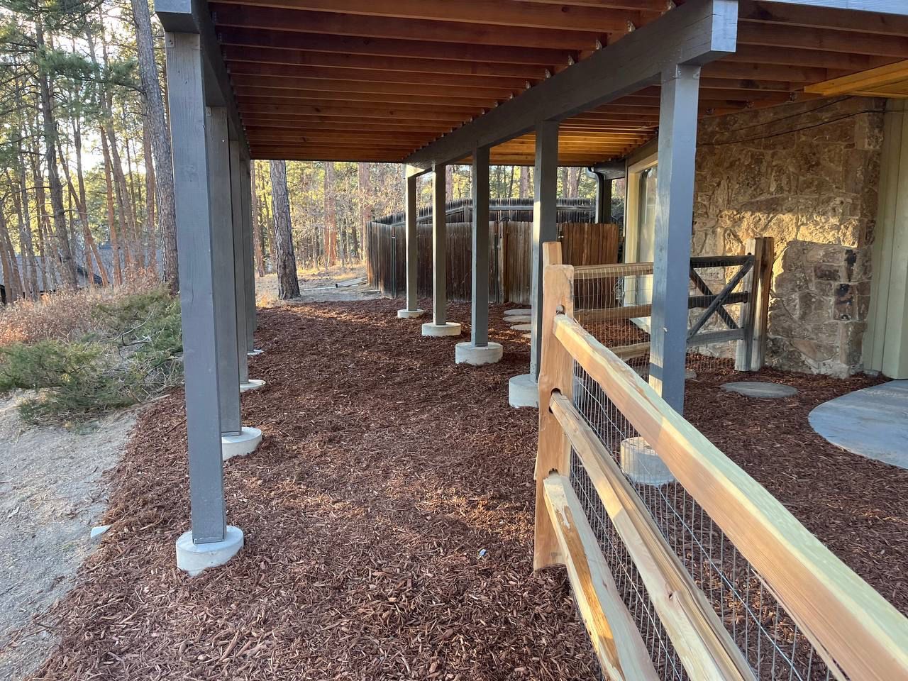 A wooden fence surrounds a covered area under a house