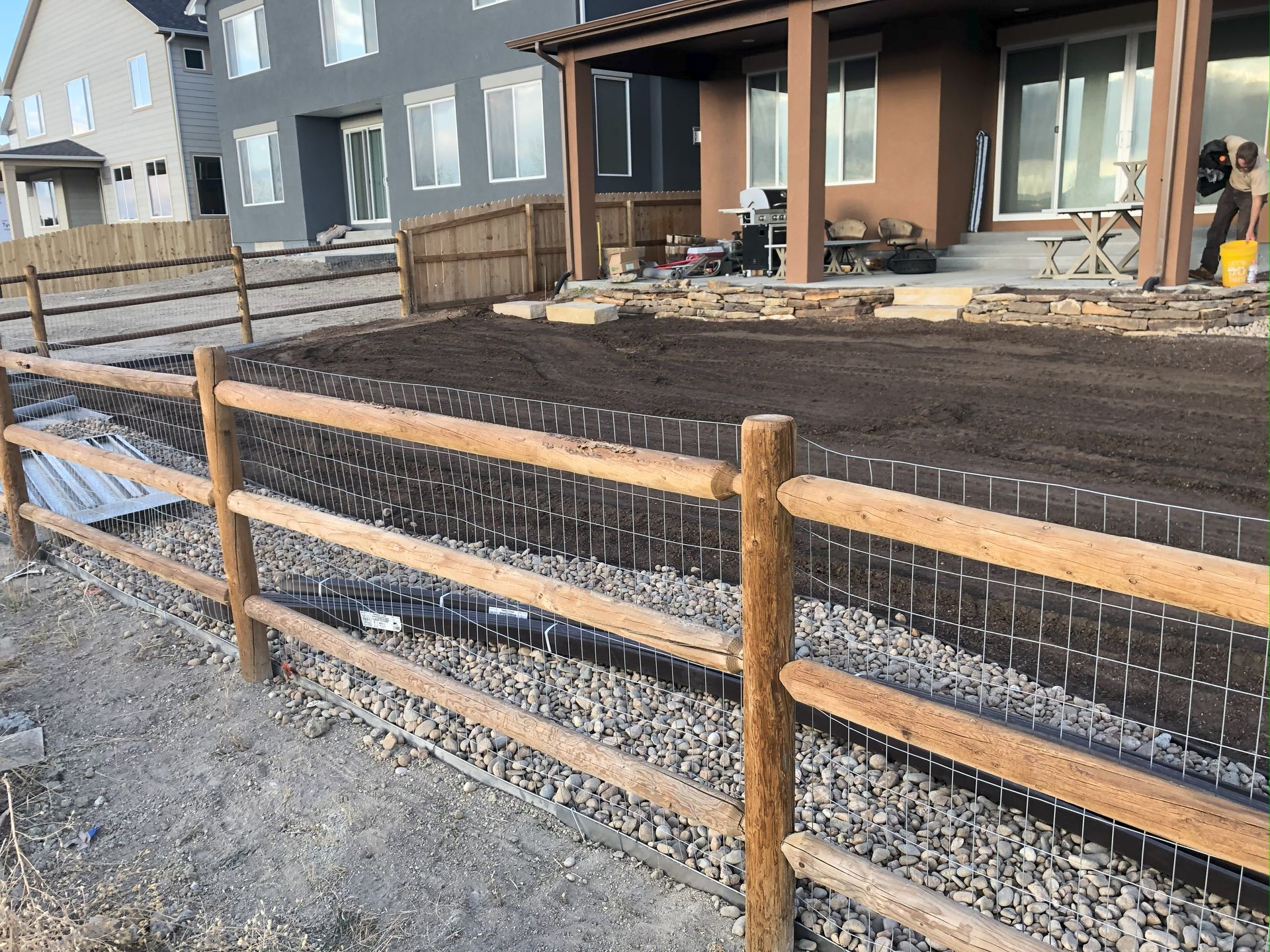 A wooden fence is in front of a house under construction