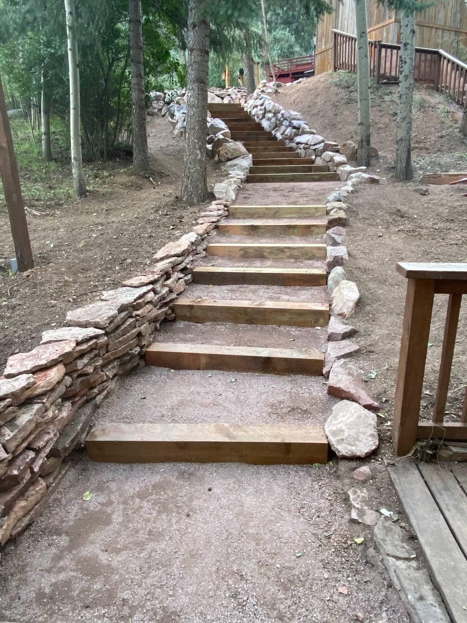 A set of wooden stairs leading up to a stone wall.