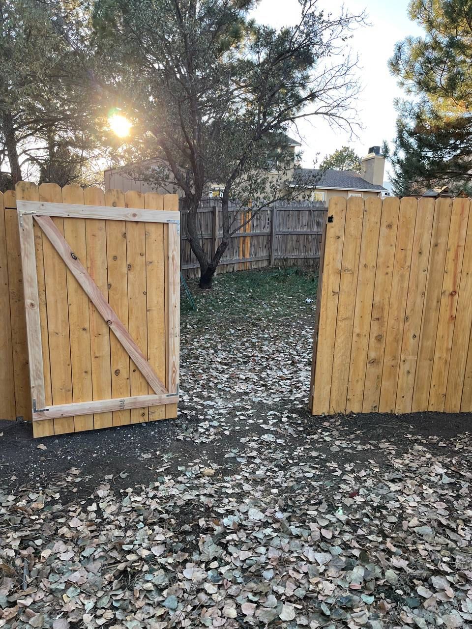 A wooden fence with a gate in the middle of it.