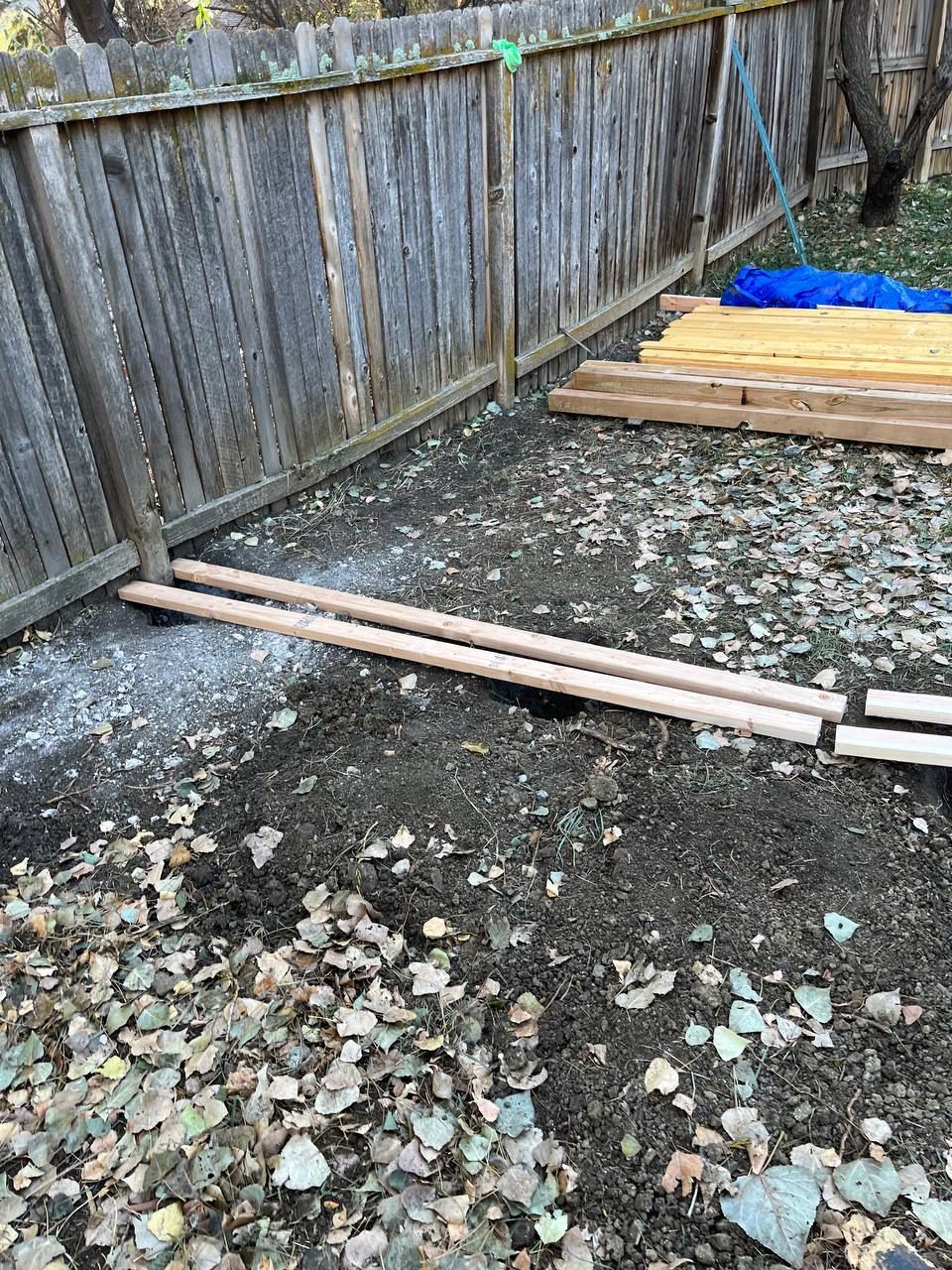 A wooden fence is surrounded by a pile of wood.