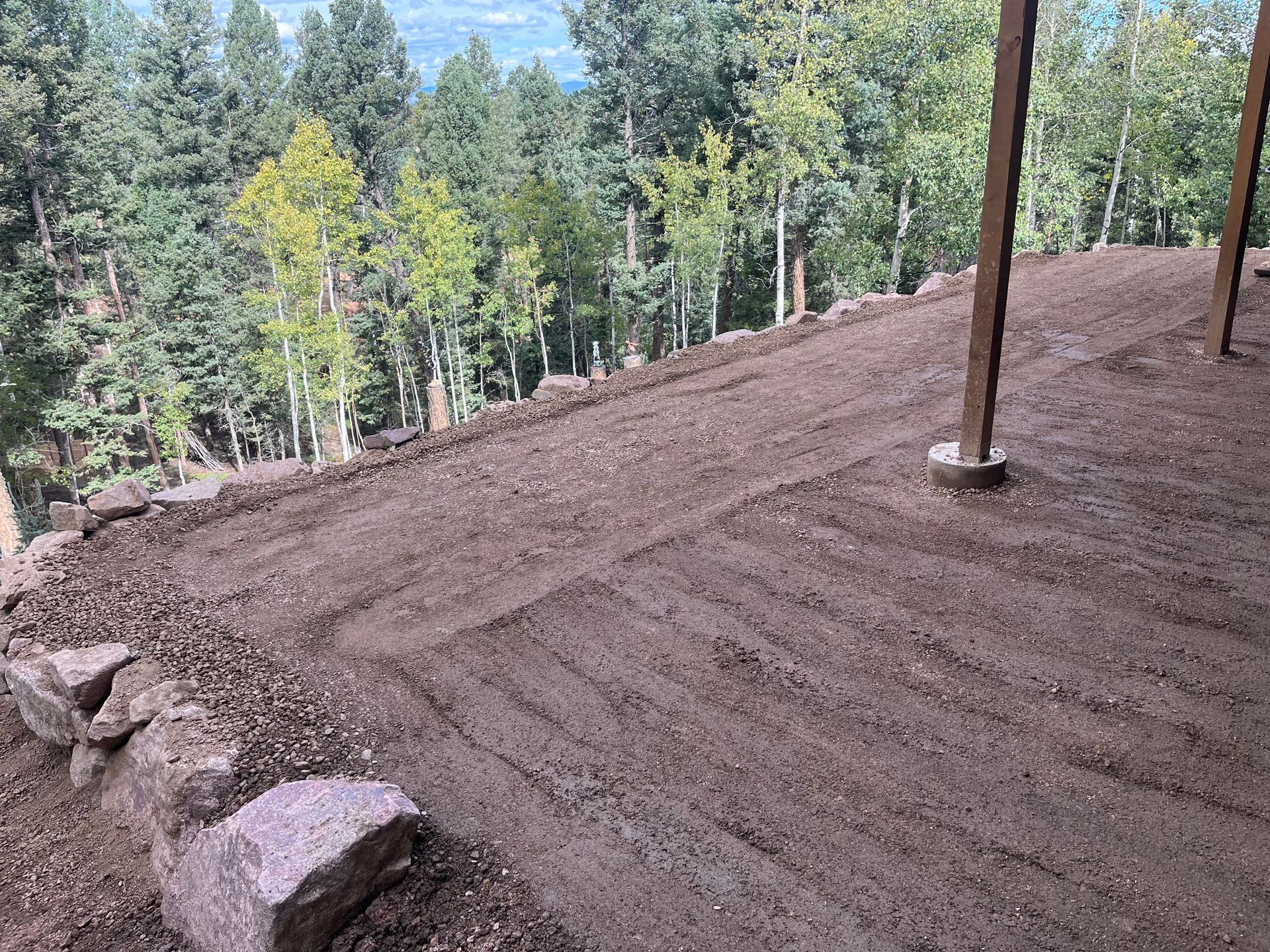 A pile of dirt and rocks on top of a hill with trees in the background.