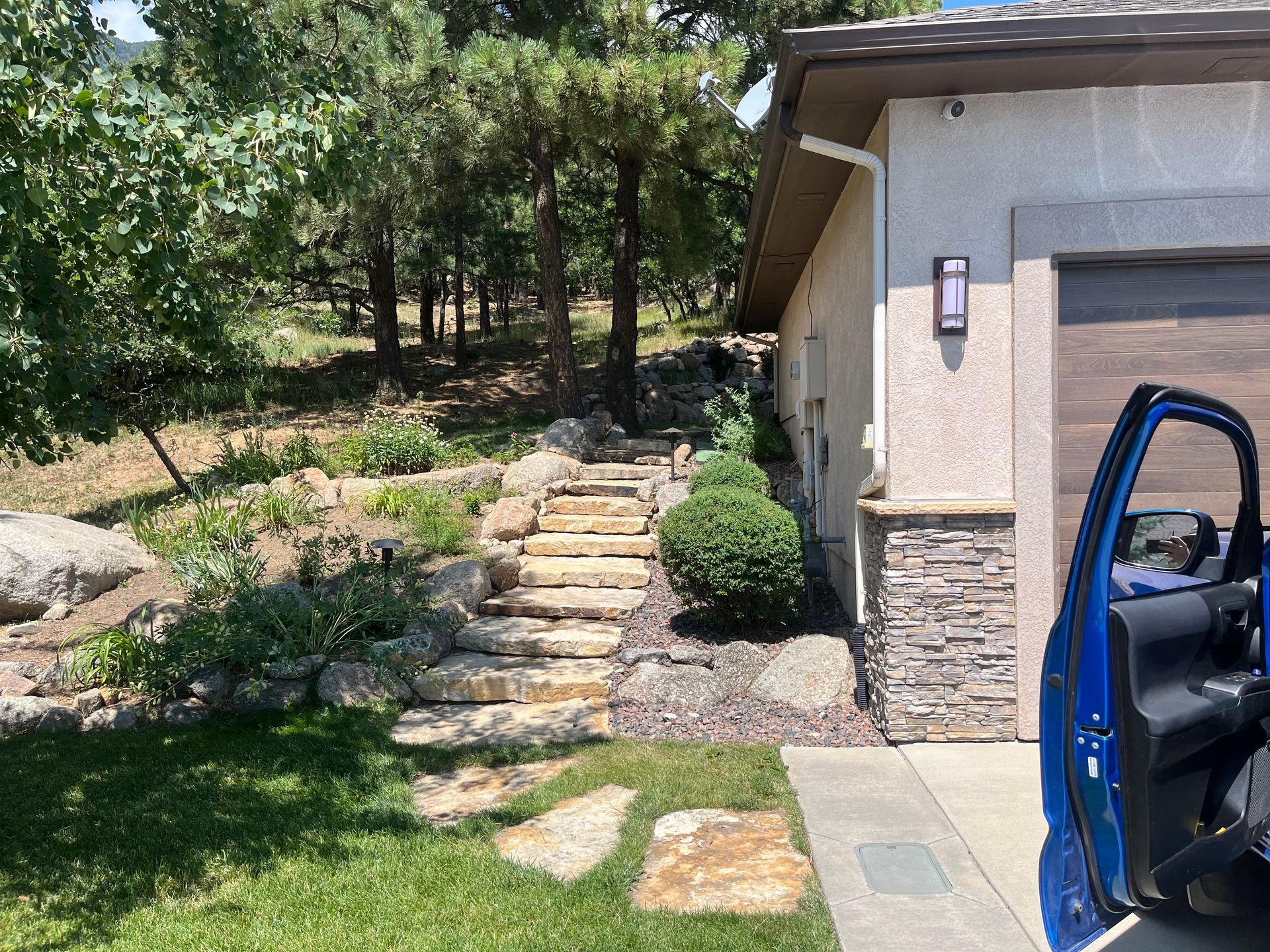 A blue car is parked in front of a garage