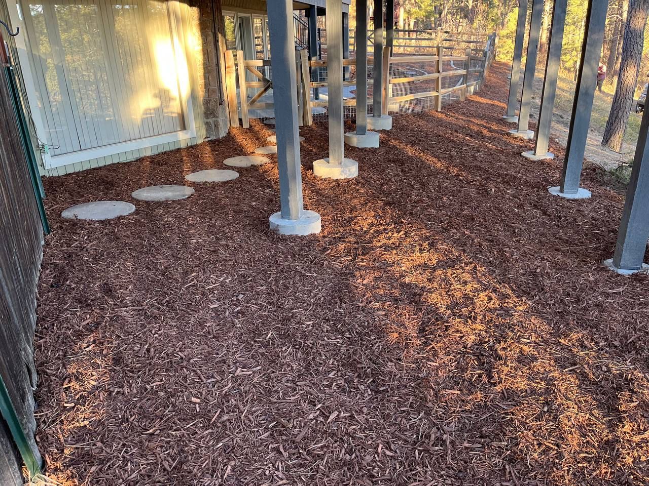 A pile of wood chips on the ground under a fence