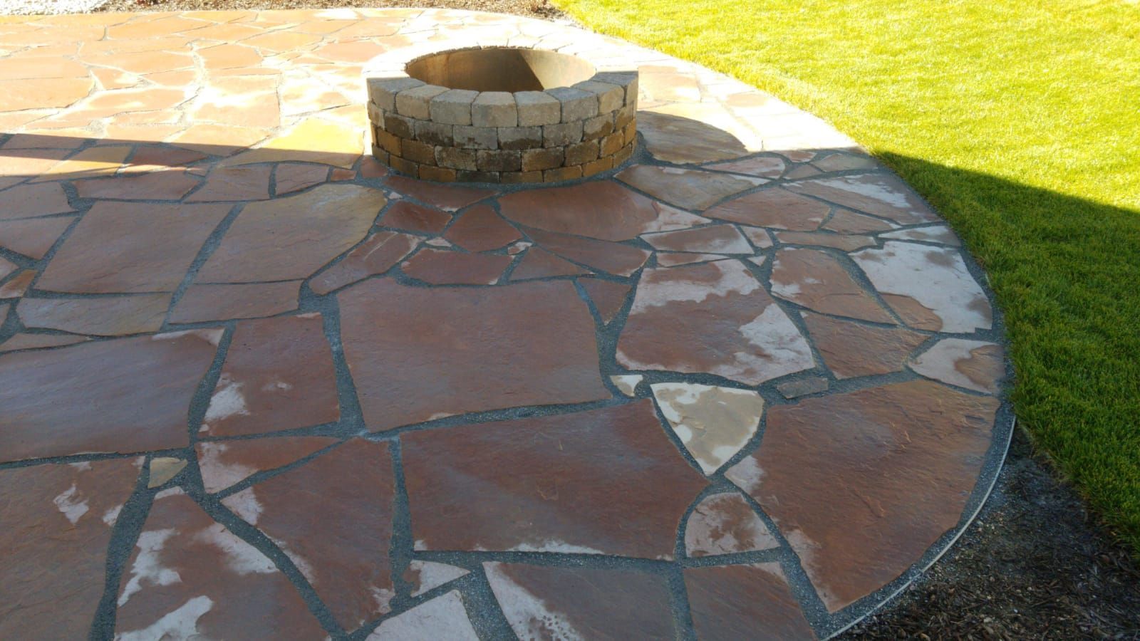 A stone patio with a fire pit in the middle