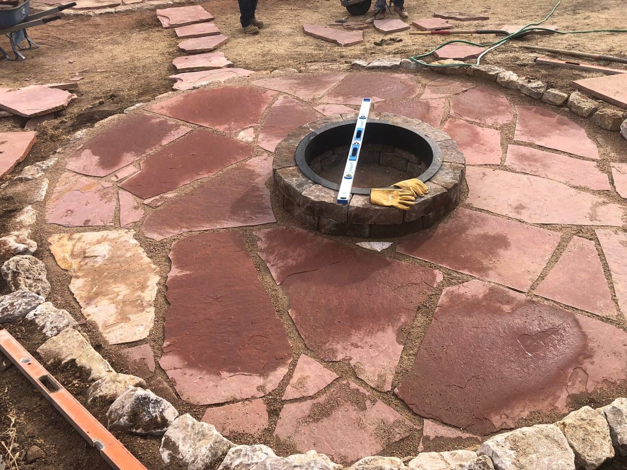 A fire pit is in the middle of a stone patio.