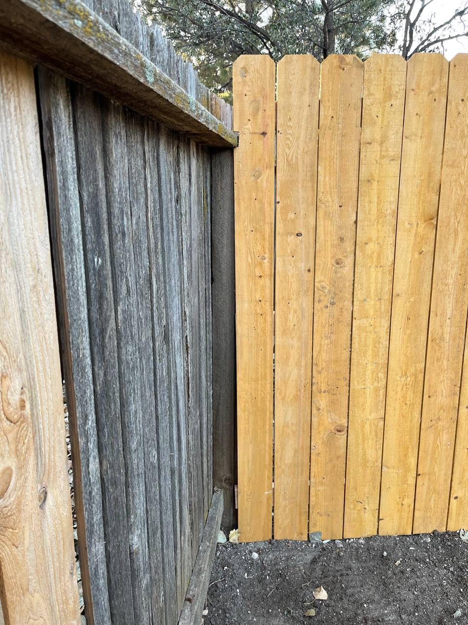 A wooden fence with a gray fence behind it
