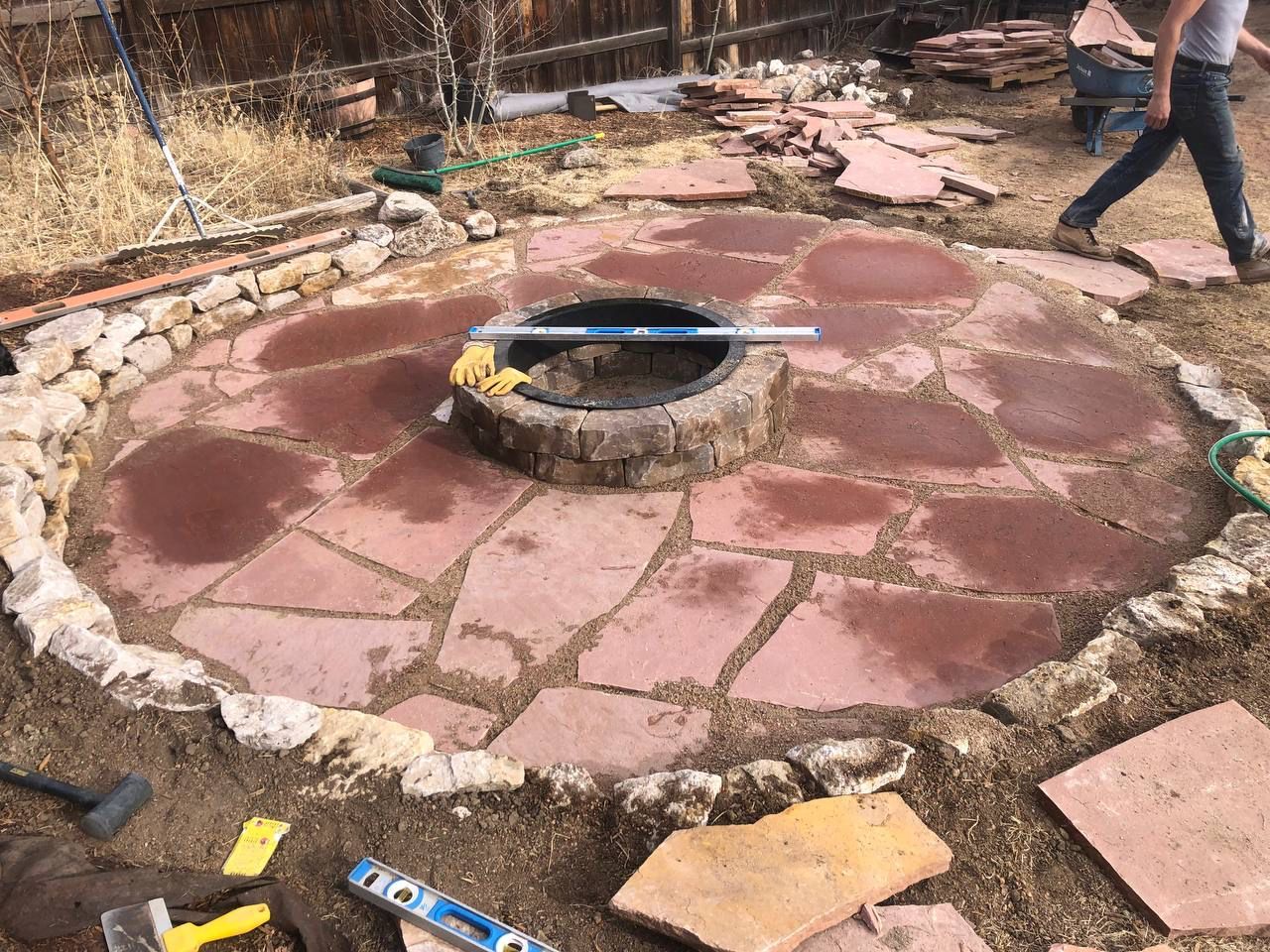 A man is working on a fire pit in a circle of rocks.
