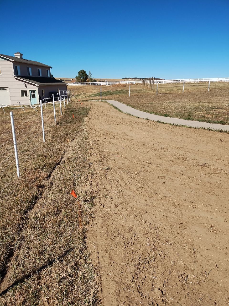 A dirt road with a house in the background